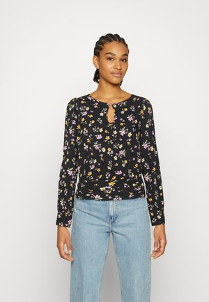 Top preto de mangas longas com detalhe em forma de fenda, apresentando um padrão floral em rosa e amarelo. Tecido suave com design de cintura franzida.