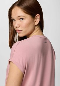 T-shirt rosa chiaro a maniche corte con scollatura tonda e un piccolo logo sulla schiena, realizzato in un materiale morbido e liscio.