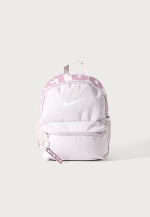 Sac à dos Nike rose clair avec poche avant zippée, logo Nike blanc, porte-clés "Just Do It" et poignée supérieure sur fond uni.