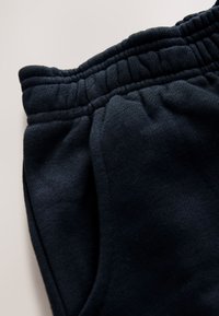 Sorte joggers i bomuld med ribbet taljebånd, sidelommer og en blød, børstet tekstur. Stoffet har en let tekstureret overflade.