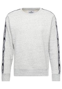 Ljust grå Hollister crewneck sweatshirts med svarta sidostycken som har upprepat vitt "Hollister"-text på båda ärmarna.