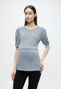 Ανοιχτό γκρι, υφασμάτινο τοπ εγκυμοσύνης με κοντά φουσκωτά μανίκια, στρογγυλή λαιμόκοψη και ρυτιδωμένη λεπτομέρεια στη μέση, σε συνδυασμό με μαύρο εφαρμοστό παντελόνι.