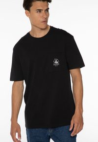 Zwarte katoenen T-shirt met korte mouwen en een ronde halslijn. Bevat een linkerborstzak met een wit berglogo en tekst.