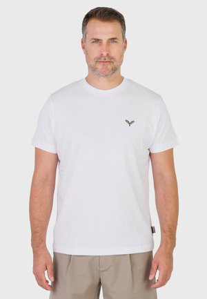 Man draagt een effen wit T-shirt met korte mouwen en een klein groen geborduurd logo op de borst, gecombineerd met beige korte broek.