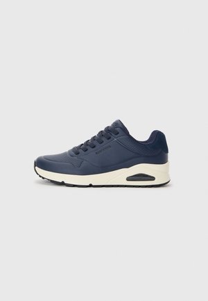 Navy blue athletic shoes with a smooth texture, featuring perforated accents, lace-up design, and a white midsole with a visible air pocket.