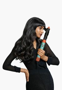 Automatisk locktång i teal och orange med en svart cylinder. Handtaget har ett texturerat grepp. Modell visar hårstylingsmetod.