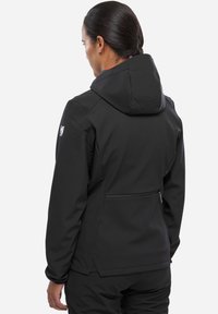 Veste softshell noire avec capuche, dotée d'une poche arrière zippée, d'épaules sans coutures et d'un ourlet réglable.
