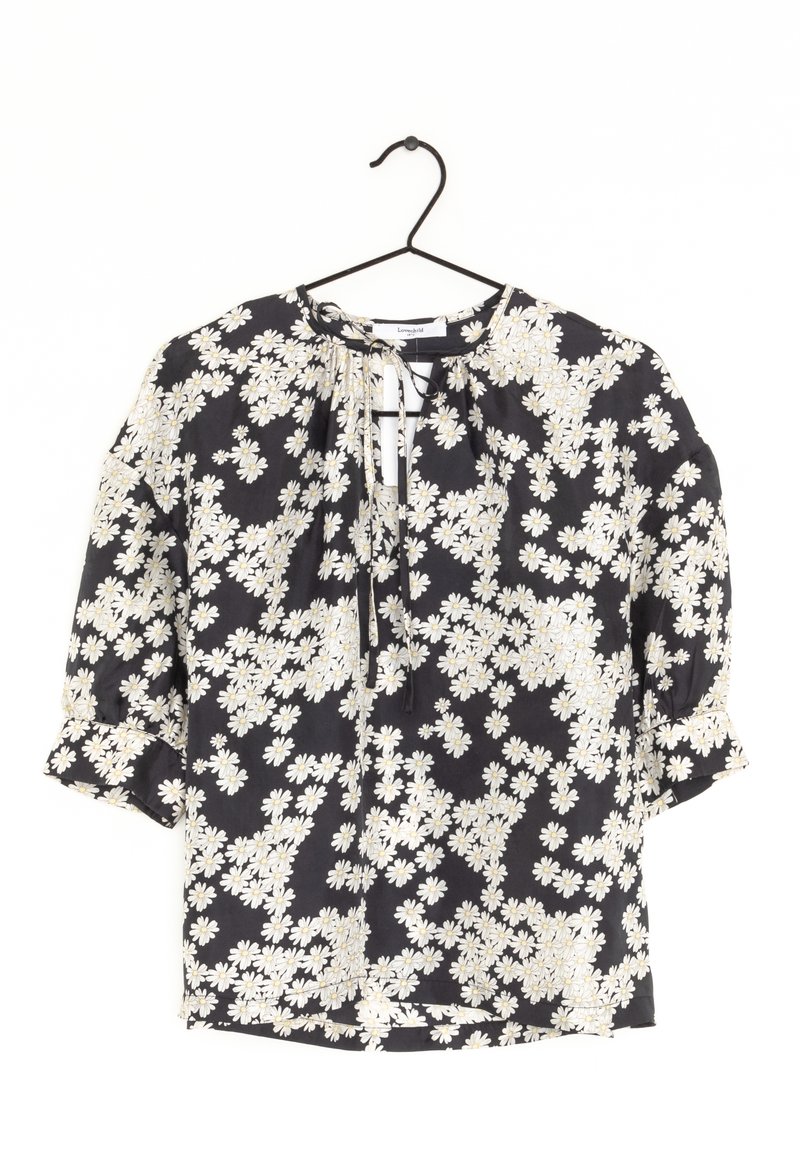 Blouse noire à motif floral blanc, tissu léger, encolure ronde avec liens, manches mi-longues et détails à volants.