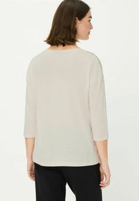 Beige, lichtgewicht top met driekwartmouwen, een ronde halslijn en een textuurpatroon langs de schoudernaden. Gladde stof, relaxte pasvorm.