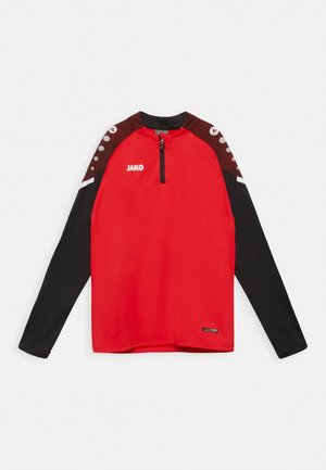 Haut de sport rouge à manches longues avec un corps noir, col zippé quart, et un design d'épaule contrasté avec des points. Logo "JAKO" à l'avant.