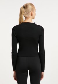 Svart ribbad långärmad tröja med en åtsittande design och en kortad skärning, med hög hals och textilstruktur.