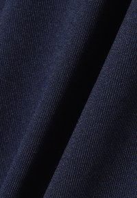 Tissu texturé bleu foncé avec un motif étroitement tissé, présenté en plis doux mettant en valeur son épaisseur et sa finition mate.