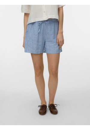 Vrouw draagt blauw-witte korte broek met verticale strepen en trekkoord, crème kort mouwtjes overhemd met knopen, en bruine veterlaarzen.