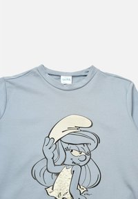 Sudadera de color azul claro con un gráfico de un personaje de los Pitufos con un sombrero blanco, contorneado en negro, y una textura brillante en el diseño.