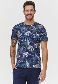 Granatowa koszulka z krótkim rękawem z tropikalnym wzorem liści i ptaków w kolorach zielonym, niebieskim i białym. Bawełniana tkanina z okrągłym dekoltem i prostym krojem.