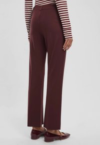Pantaloni sartoriali bordeaux con una trama liscia, design a gamba dritta e tasche posteriori. Indossati con ballerine lucide bordeaux.