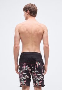 Mustad lauašortsid roosa ja rohelise lillemustriga. Valmistatud kergest materjalist, varustatud veniva vöökohaga ja küljetaskuga.