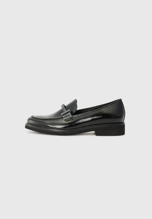 Mocassins en cuir verni noir avec un bout rond, un talon bas et un matériel en métal décoratif à l'avant. Texture lisse, design minimal.
