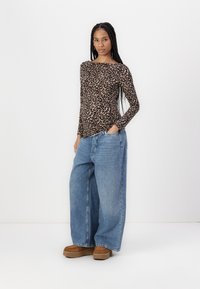 Black and tan leopard print long-sleeve top paired with light blue wide-leg jeans, and brown platform shoes. Simple and casual outfit.