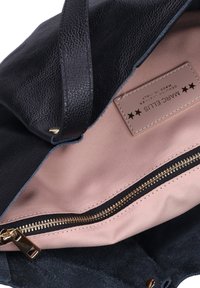 Borsa tote in pelle nera con superficie liscia, fodera rosa pallido, zip dorata e etichetta del marchio cucita all'interno.