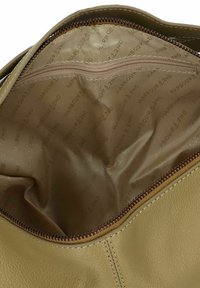 Interno di borsa in pelle verde oliva con una texture liscia, dotato di chiusura a zip e rivestimento di un beige chiaro a contrasto. Logo stampato all'interno.