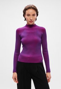 Suéter roxo com nervuras, gola alta e mangas compridas. Textura suave com um degradê do roxo escuro para o roxo claro. Design ajustado.