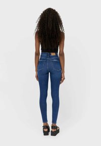 Jeans skinny de vaquero azul de talle alto con una textura suave, que cuentan con bolsillos traseros y una etiqueta de cuero con la marca en la cinturilla.