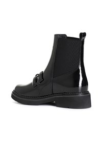 Černé kotníkové boty s lesklým patentním povrchem, elastickými bočními panely, dekorativní přezkou a masivní gumovou podrážkou.