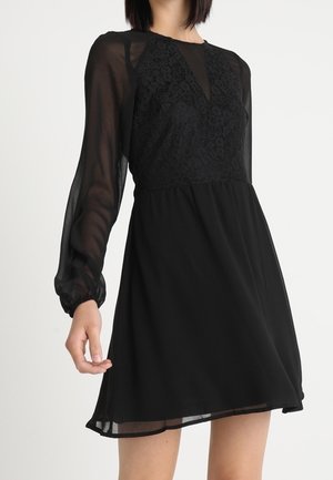 Black dress with a lace bodice, sheer long sleeves, and a flared skirt. Features a V-neckline and fitted waist, crafted from lightweight fabric.