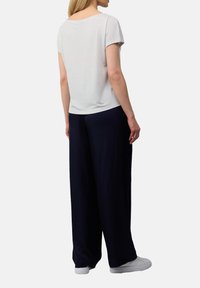 Katoenen blend t-shirt met korte mouwen in lichtgrijs, gecombineerd met losse marineblauwe broek. Glad textuur, ronde halslijn en eenvoudig ontwerp.