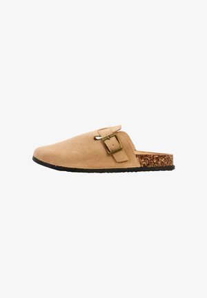 Tanfarvet ruskind slip-on træsko med justerbar metalspænde, kork-fodseng og sort gummisål vist fra siden.