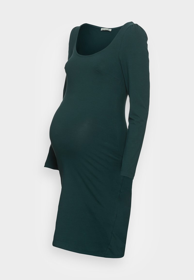 Mörkgrön, långärmad gravidklänning med rundad halsringning och figurnära silhuett designad för att rymma en babymage.