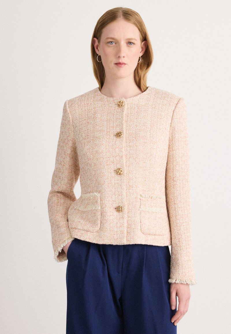 Helle rosa Tweedjacke mit rundem Ausschnitt, goldenen Knöpfen und zwei vorderen Taschen. Strukturierter Stoff mit ausgefransten Kanten. Taillierte Passform.