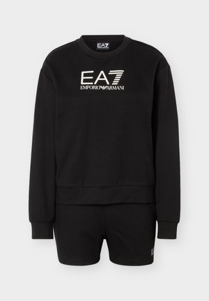 Fekete Emporio Armani EA7 pulóver és hozzá illő rövidnadrág fehér logós szöveggel, mely a mellkason középen és a rövidnadrág bal alsó részén található.