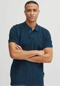Polo shirt bleu marine en coton avec un col, des manches courtes, deux boutons et un petit logo brodé sur la poitrine.