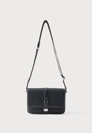 Zwarte leren crossbodytas met verstelbare riem, voorflap en zilveren gespdetail op een effen witte achtergrond.