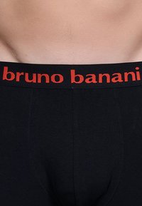 Boxer da uomo neri in cotone con una texture solida, caratterizzati da una cintura elasticizzata rossa che riporta la scritta "bruno banani" in caratteri in grassetto.