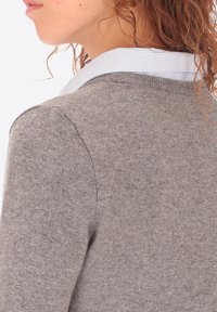 Maglione grigio lavorato a maglia con una texture morbida, caratterizzato da un colletto a righe blu chiaro. Ha un design aderente e polsini a coste.