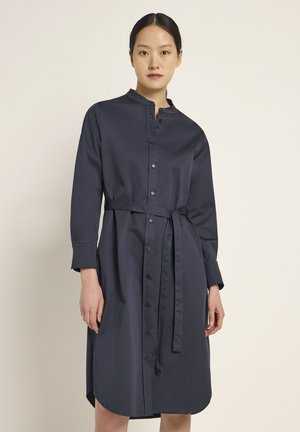Navy-blaues Hemdkleid aus glattem Stoff, mit Stehkragen, langen Ärmeln, tailliertem Schnitt mit Gürtelschlaufe und abgerundetem Saum.
