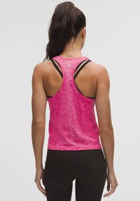 Top atletico aderente di colore rosa brillante, con un design a maglia testurizzata e dettagli di spessore neri. Stile racerback, che mette in mostra una schiena scoperta.