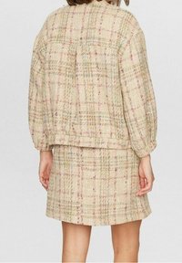 Ensemble tissé deux pièces beige avec des motifs à carreaux multicolores ; composé d'une veste à coupe décontractée et d'une jupe ajustée. Tissu texturé.