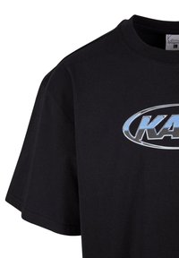 Black cotton t-shirt with short sleeves, featuring a large silver logo centered on the chest, clean neckline, and smooth texture.