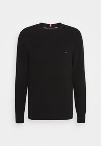 Pull noir à manches longues avec un motif de tricot texturé et un col rond. Petit logo sur la poitrine avec des accents rouges et blancs.