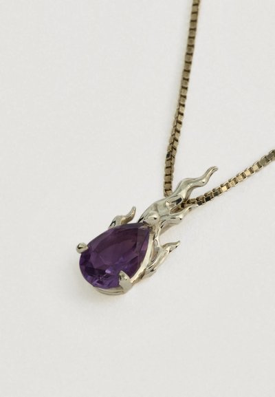Naszyjnik z złotym łańcuszkiem i zawieszką z fioletowym kamieniem szlachetnym w kształcie kropli, otoczoną artystyczną złotą oprawą przypominającą płomień, na białym tle.