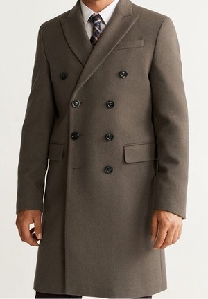 Doppelreihiger Mantel aus dunkelbraunem Wollstoff, mit schwarzen Knöpfen, Reverskragen und zwei schrägen Fronttaschen. Taillierter Schnitt.