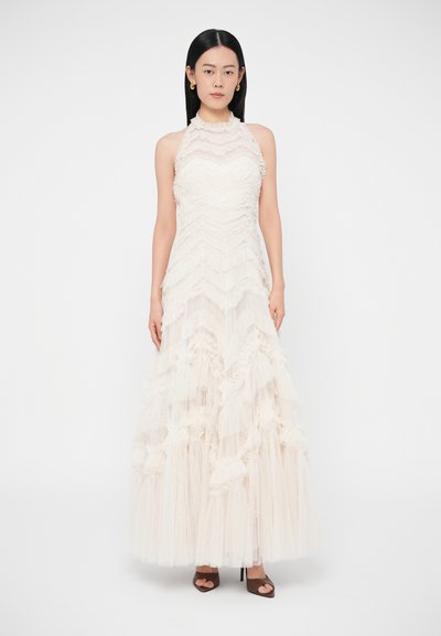 Dlhé slonovinové šaty s volánkovým vrškom, textúrovaným vzorom cikcak a viaczvrstvovou sukňou z tulu. Sú vybavené vysokým výstrihom a polopriehľadnou látkou.