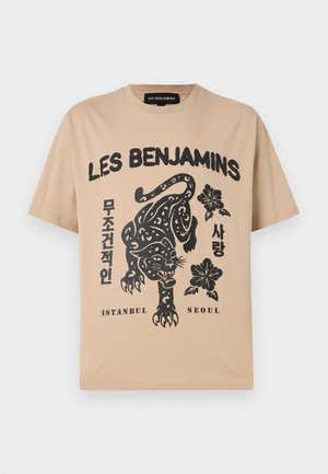 Beige T-paita, jossa musta grafiikka kyykistyneestä leopardista, kukkia, teksti "LES BENJAMINS", korealaisia merkkejä ja kaupunginimet "ISTANBUL" ja "SEOUL".