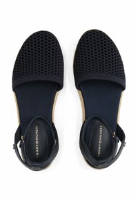 Sandalias espadrilles de color azul marino con parte superior de tela trenzada, correa elástica en el tobillo y media suela de yute. Cuentan con una suela plana y plantilla acolchada.
