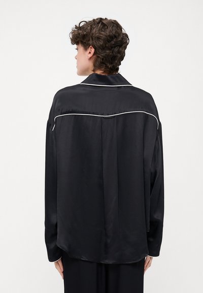 Black satin shirt featuring a classic collar, long sleeves, contrasting white piping along the seams, and a relaxed fit.