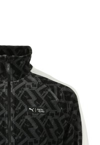 Zwarte en grijze zip-up trainingsjack met geometrische patronen, een hoge kraag en witte accenten. Inclusief een logo met "Puma" en "Squid Game."